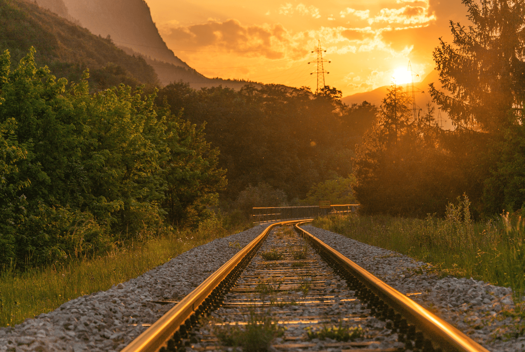 Image of a train track in a rural area at sunset
