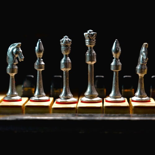 Silver chess pieces on a board with black background.