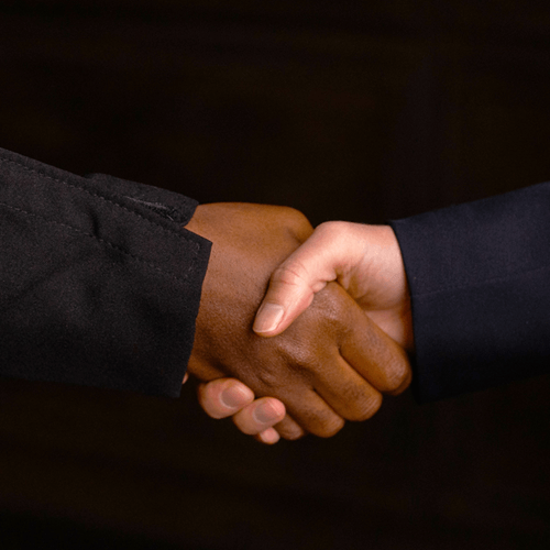 Two people in black jackets shaking hands.
