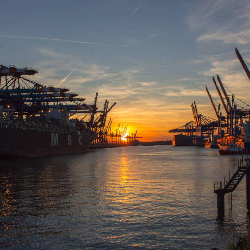 Image of shipping cranes at sunset over the water